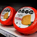 Ruedas de queso en estante refrigerado.webp